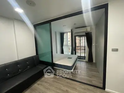 Modern apartment with glass partition and balcony view, featuring sleek furnishings and natural light.