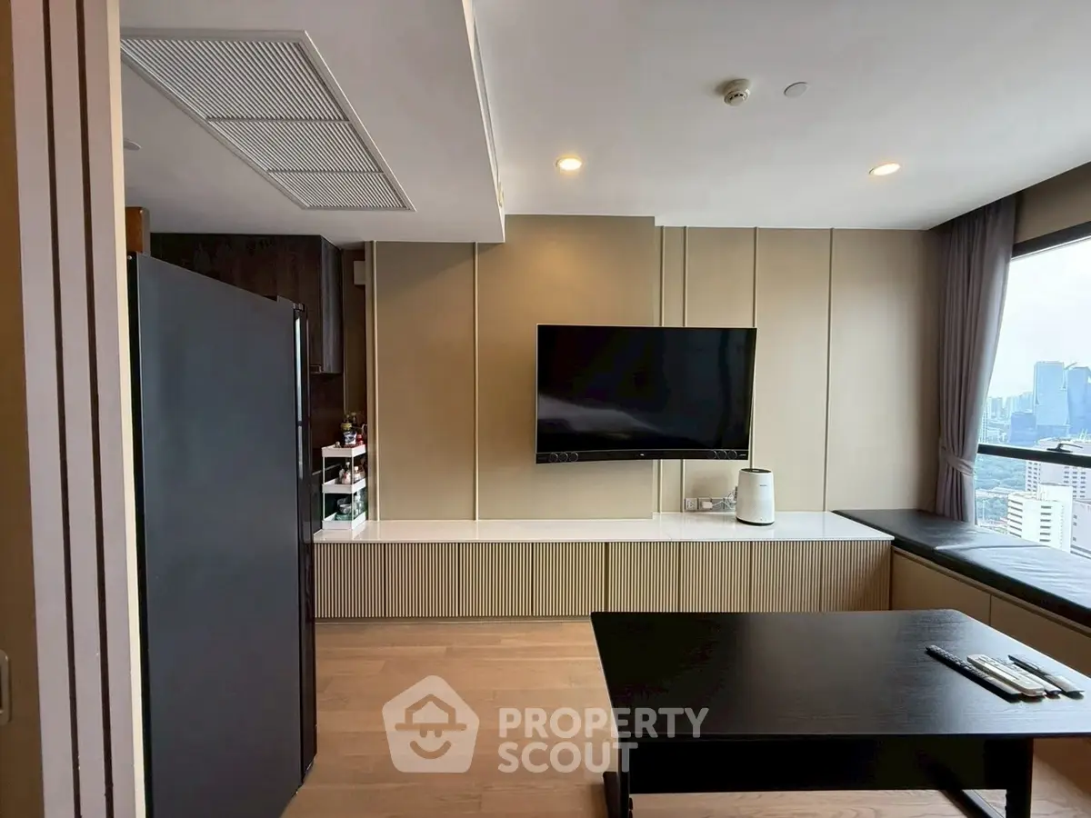 Modern living room with sleek TV setup and city view, featuring stylish furniture and ample natural light.