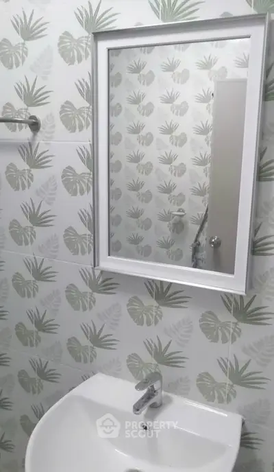 Modern bathroom with stylish leaf-patterned tiles and sleek white fixtures.
