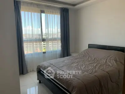 Cozy bedroom with large window offering stunning city views, perfect for relaxation and comfort.