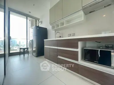 Modern kitchen with sleek cabinetry, large window, and city view, featuring fridge and microwave.