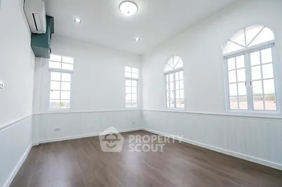 Spacious bright room with elegant arched windows and wooden flooring