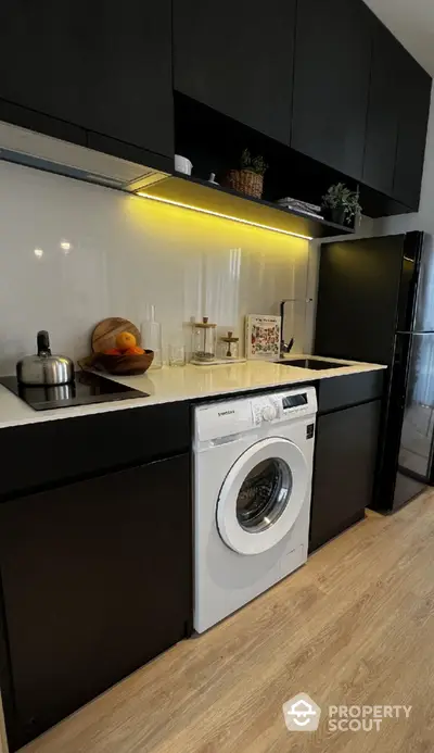 Modern kitchen with sleek black cabinets and built-in washing machine