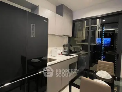 Modern kitchen with sleek black appliances and dining area in contemporary apartment.