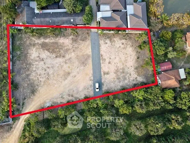 Aerial view of a vacant plot of land outlined in red, ideal for development.