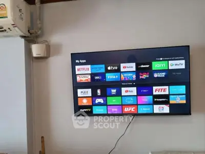 Modern living room with wall-mounted smart TV and air conditioning unit.