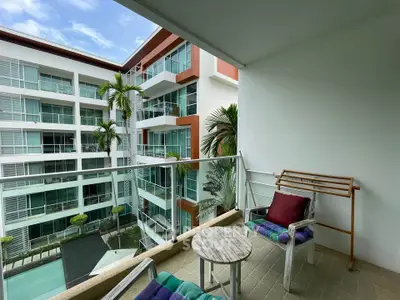 Spacious balcony with modern furniture overlooking a luxurious apartment complex and pool.