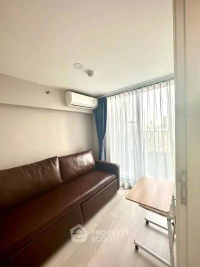 Cozy living room with brown leather sofa and large window with blue curtains