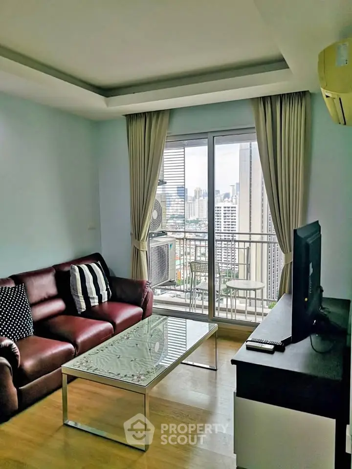 Modern living room with city view, featuring a leather sofa and glass coffee table.