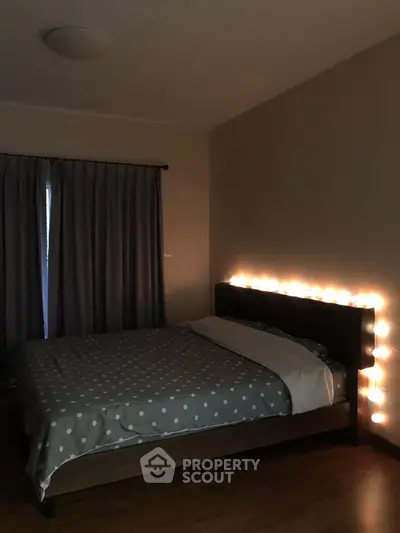 Cozy bedroom with ambient lighting and polka dot bedding, perfect for relaxation.