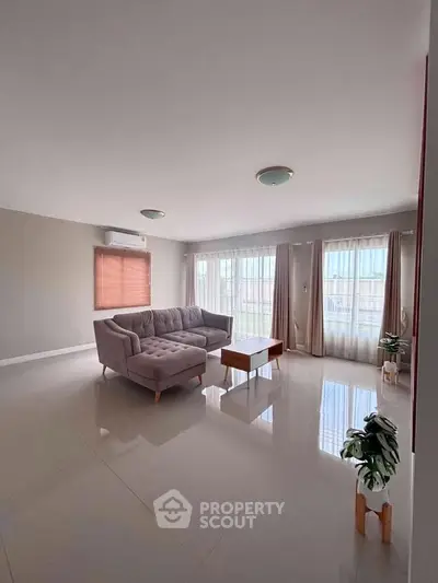 Spacious living room with modern sofa and large windows offering natural light.