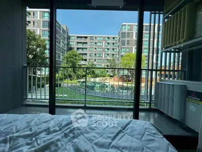 Modern apartment with pool view from bedroom, featuring large windows and lush greenery.