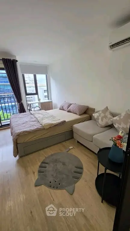 Cozy bedroom with modern decor and city view, featuring a comfortable bed and stylish sofa.