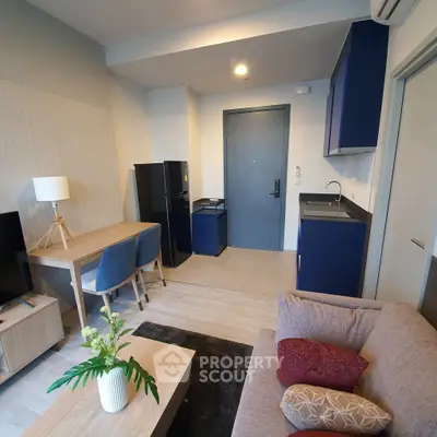 Modern living room with stylish furniture and compact kitchen area in a cozy apartment.