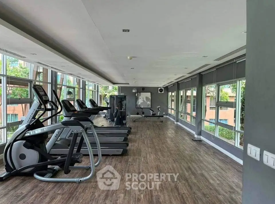 Spacious modern gym with large windows and state-of-the-art equipment in a residential building.