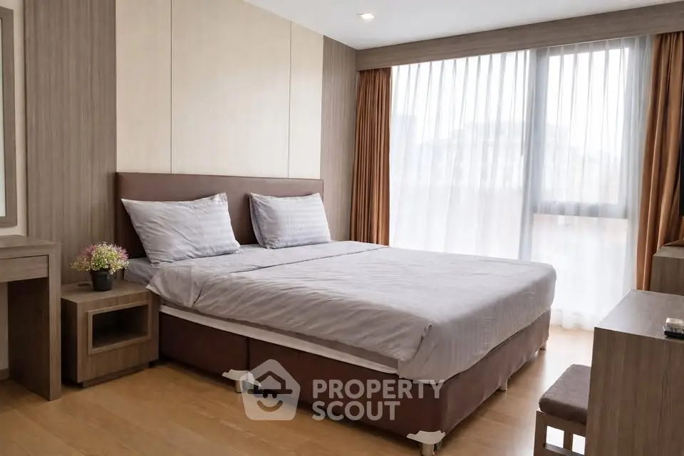 Modern bedroom with large window and stylish decor in a contemporary apartment.