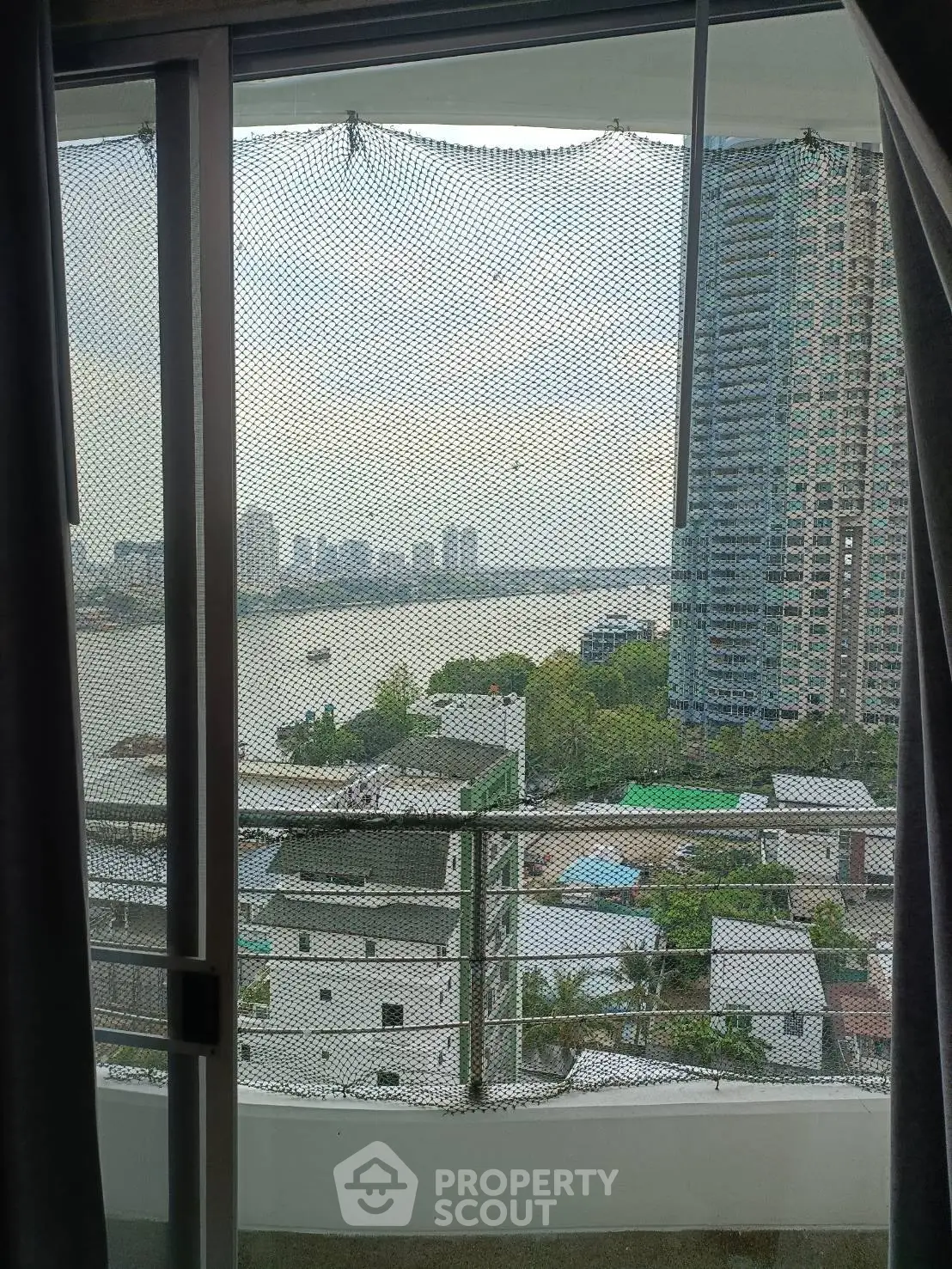 Stunning high-rise balcony view overlooking river and cityscape, perfect for urban living.