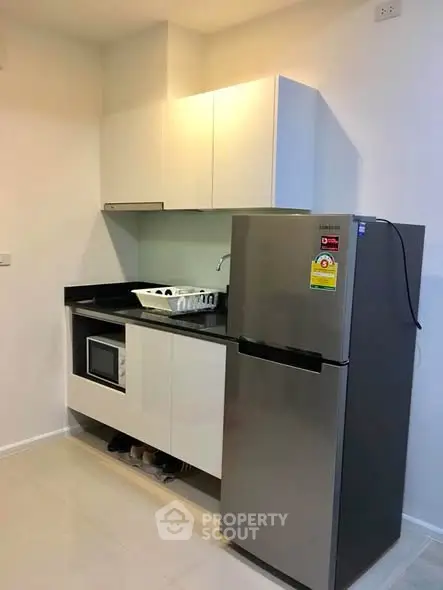 Modern kitchen with sleek cabinets and stainless steel fridge in compact layout.