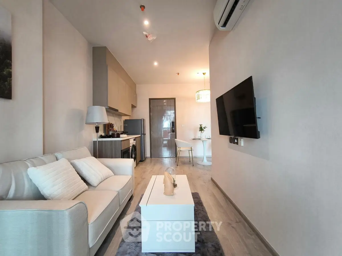 Modern living room with sleek furniture and open kitchen layout in a stylish apartment.