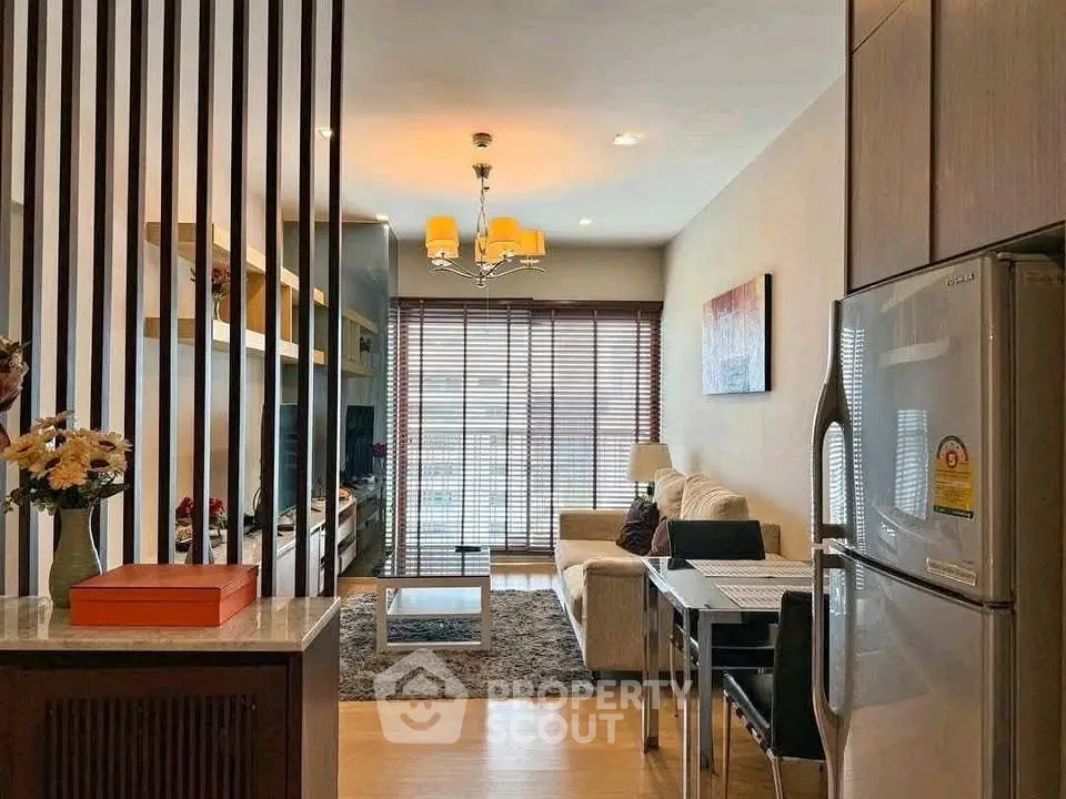 Modern living room with open kitchen, stylish decor, and natural light from large windows.