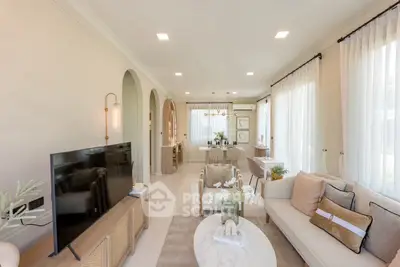 Elegant living room with modern decor and natural light, featuring a cozy seating area and stylish TV setup.