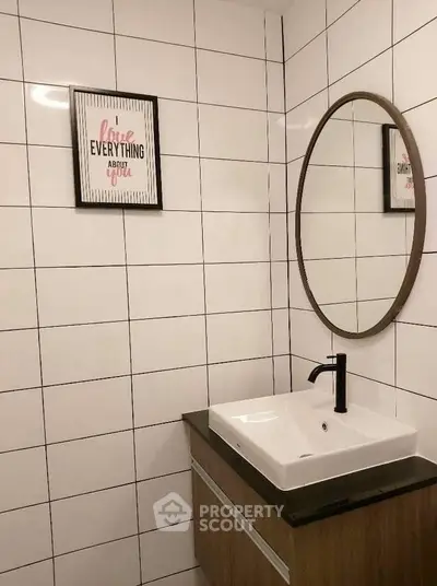 Modern bathroom with stylish sink and round mirror, featuring sleek tile design.