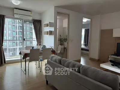 Modern apartment interior with open living and dining area, featuring large windows and stylish decor.