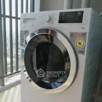 Modern washing machine in a bright laundry area with large windows.