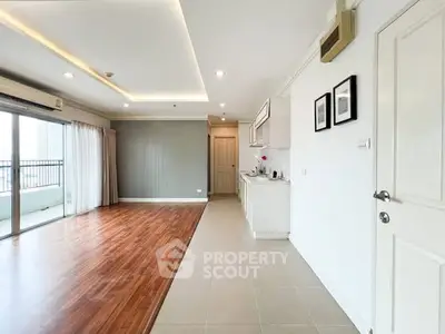 Spacious open-plan living room with kitchen and balcony access, featuring modern design and ample natural light.