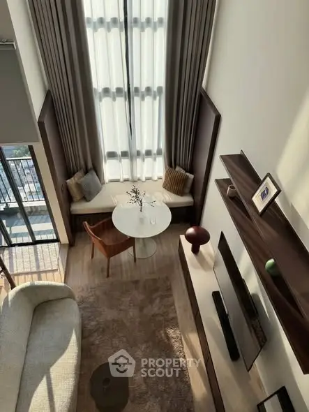 Luxurious living room with high ceilings and elegant decor, featuring a cozy seating area and large windows.