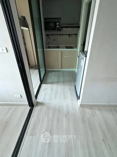 Modern compact kitchen with sleek appliances and light wood flooring