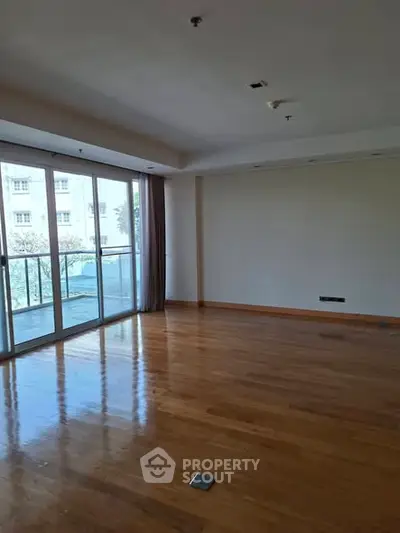 Spacious empty living room with large windows and wooden flooring