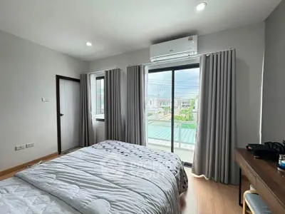 Modern bedroom with large window and air conditioning, featuring stylish decor and natural light.