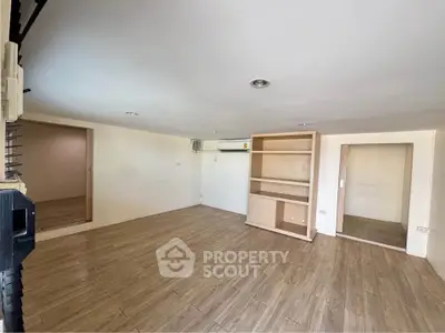 Spacious room with wooden flooring and built-in shelving, ideal for versatile living space.