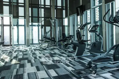 Spacious modern gym with state-of-the-art equipment and floor-to-ceiling windows offering city views.