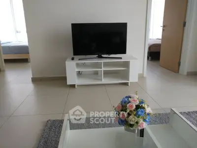 Modern living room with TV and floral centerpiece, open layout to bedroom