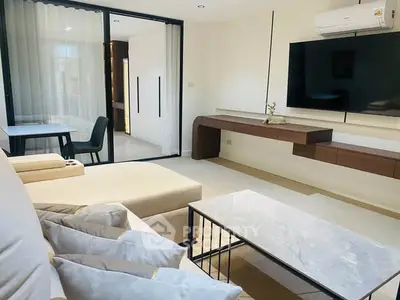 Modern living room with sleek furniture and large TV, perfect for relaxation and entertainment.
