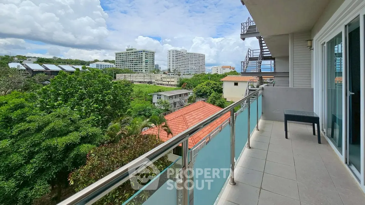 Spacious balcony with scenic view of lush greenery and modern buildings.