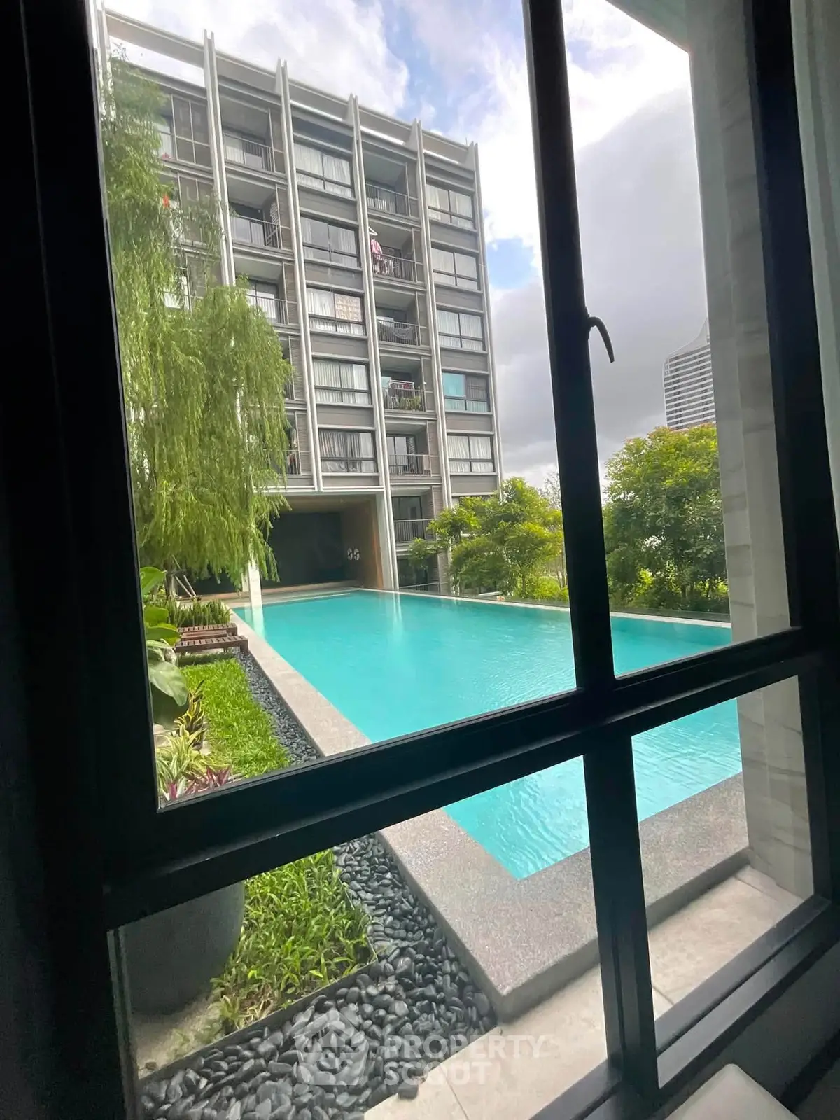 Luxurious apartment view with serene pool and lush greenery, perfect for relaxation and modern living.