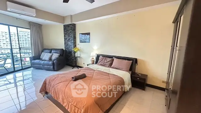 Spacious bedroom with balcony access and modern furnishings in a high-rise apartment.