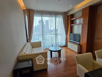 Modern living room with city view, featuring elegant furniture and floor-to-ceiling windows.