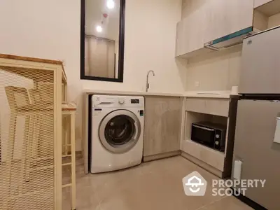 Modern kitchen with washing machine, microwave, and fridge in compact layout