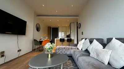 Modern living room with stylish decor and open kitchen layout, featuring a cozy sofa and dining area.