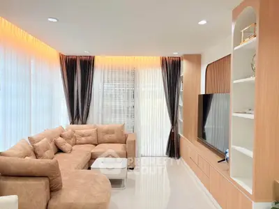 Modern living room with elegant beige sofa and large TV unit, featuring ambient lighting and floor-to-ceiling windows.