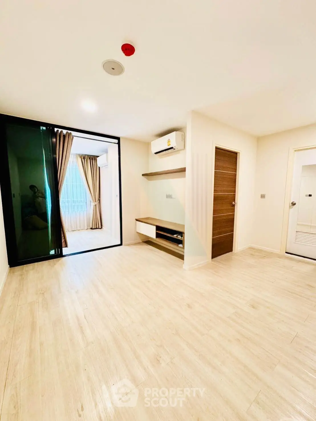 Spacious modern living room with wooden flooring and large windows for natural light.
