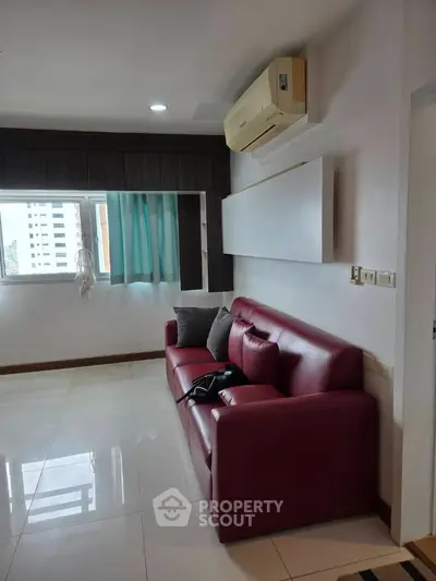 Modern living room with red leather sofa and air conditioning, featuring large window with city view.