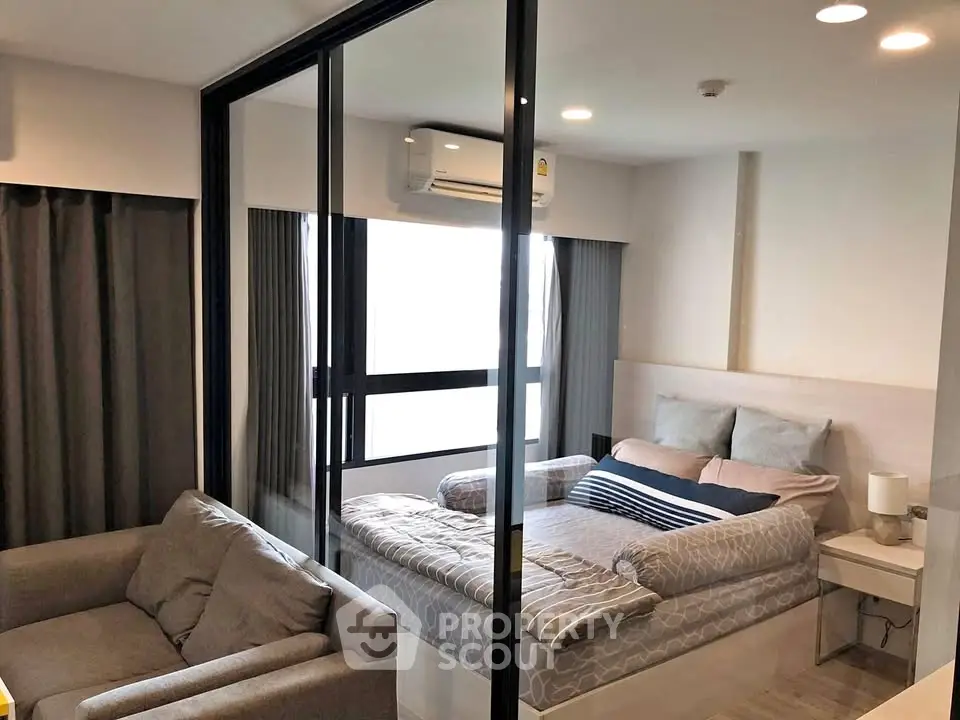 Modern bedroom with glass partition and cozy furnishings in a stylish apartment.