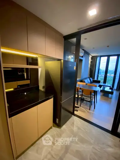 Modern open-layout kitchen with sleek appliances and view into stylish living room with large windows.