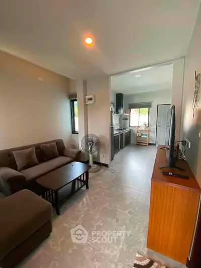 Cozy living room with modern decor and open kitchen layout, perfect for comfortable living.