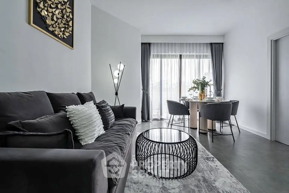 Modern living room with stylish decor and natural light, featuring a cozy sofa and elegant dining area.